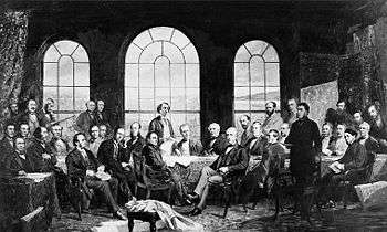men gathered around conference table in front to windows
