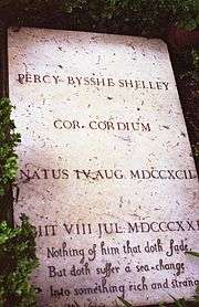 Color photograph of Percy Shelley's flat, rectangular, marble tombstone, which reads "Percy Bysshe Shelley Cor Cordium Natus IV Aug MDCCXCII [Ob]iit VIII Jul MDCCCXXI[I] Nothing of him that doth fade, / But doth suffer a sea change / Into something rich and strange."