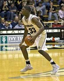 an African American basketball player in a Purdue #33 jersey is dribbling a basketball