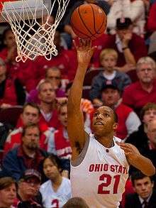 an African American wearing Ohio State jersey #21 attempts a one handed shot from the side of the basket.