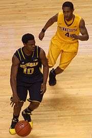 Player in brown uniform dribbling, pursued by player in yellow uniform