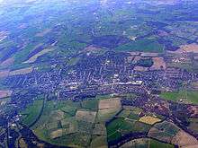 aerial picture of the town surrounded by green fields.