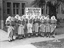 A group of nurses stand in front of a brick building