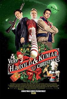 Two Asian men stand on either side of Neil Patrick Harris holding a candy cane like a gun.