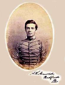 Head and shoulders of a young white man with thick hair and a smirk, wearing a jacket with stripes on the upper sleeves and decorative cords running horizontally across the chest. The words "A.K. Arnold, Bedford, Pa." are written at lower right.