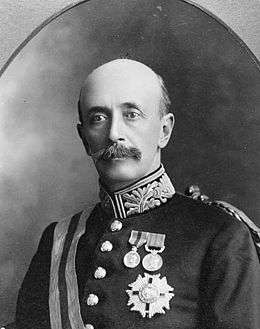 Upper body of a bald man with a large moustache.  He is in a military uniform with several medals pinned to his left chest.