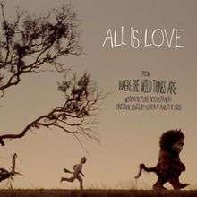 A sparse landscape at dusk. In the center, a young boy dressed in a monster costume runs to catch up with a monster a few yards before him. Above the monster's head are the words "All is Love" in white and, below those, the words "From Where The Wild Things Are Motion Picture Soundtrack Original Songs by Karen O and The Kids" written in black. The left side of the image features a tree with bare branches which extend over the boy's head.