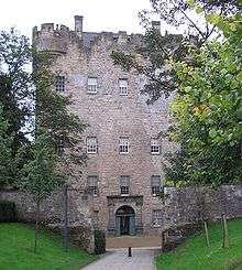 A tall stone building from the 15th century with trees bordering to the sides