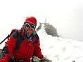 man on summit of mountain wearing alpine climbing equipment