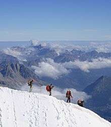 Mountaineers descending steep snow ridge above Chamonix