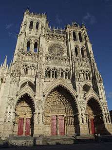 A very tall cathedral with three large entrances.