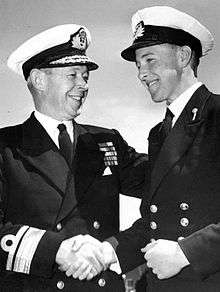 Two men in full winter naval uniform, shaking hands