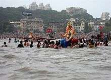 Large statue of Ganesha on the water, surrounded by people
