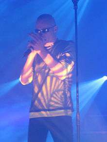 A male singer wearing sunglasses performing on stage