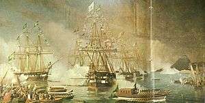 A painting depicting tall-masted sailing ships dressed with flags in the background, some of which are firing cannon salutes, and a large covered launch flying a huge green flag being rowed towards the shore, followed by a crowd of smaller craft