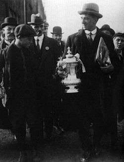 An elderly man holding the FA Cup