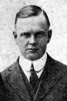 Head and shoulders of white middle aged man in 1920s suit and tie