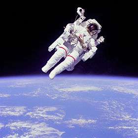 The lower half shows a blue planet with patchy white clouds. The upper half has a man in a white spacesuit and maneuvering unit against a black background.