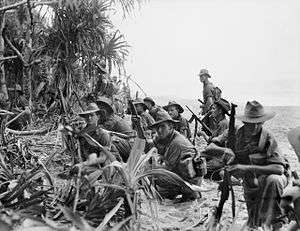 Soldiers resting on a river bank on the edge of the jungle