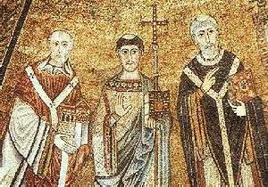 Mosaic image of three men dressed in elaborate robes. The central figure has a tonsure and is holding a cross-topped staff and closed book in one hand and his other hand is held upright, palm out. The left figure is bald and holds a model of a church in both hands. The right figure is tonsured and holds a book in one hand and makes a gesture with his other hand.