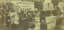 a monochrome photo of a protest rally.  Many of the protesters are minorities, and have Afro hairstyles.  "WOMEN AGAINST BAKKE" is a typical sign being held.