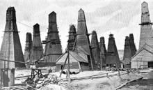A black-and-white photograph showing a field of derricks each completely enclosed within its own oddly shaped wooden building.