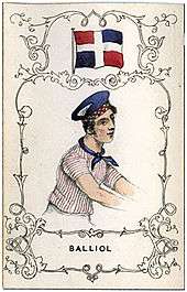 A man wearing a blue neckerchief and hat, and a jersey with thin vertical stripes, under flag with red and blue in opposite quadrants, divided by a white cross running top to bottom and left to right