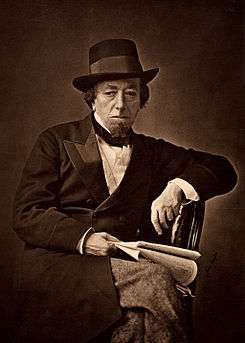 Disraeli in old age, wearing a double-breasted suit, bow tie and hat