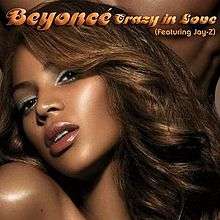 Left side of the face of a brunette woman with soft make-up. Behind her, the chest of a naked man is visible. The words "Beyoncé," "(featuring Jay-Z)" and "Crazy in Love" are written above her image.