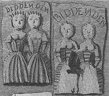Two rectangular cakes, one showing two women apparently conjoined at the shoulder and the other one damaged in such a way that it is not clearly apparent whether the women are conjoined. Each cake has the word "Biddenden" written above the women.