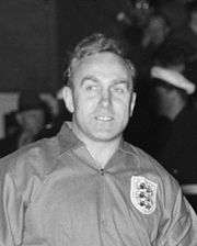A black and white photograph of Billy Wright, wearing an England national team jersey.