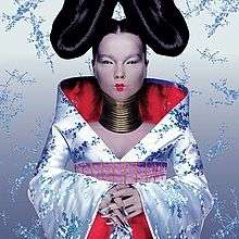 A picture of the album cover depicting a silver background with Björk standing facing forward in the middle. Björk is dressed in a outfit resembling a Kimono wearing large rings around her neck, silver fingernails and a large bun shaped hair style on each side of her head.