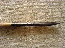 A wooden shaft is tipped with a narrow metal piece sharpened to a point.