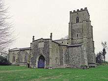 A stone church seen from the north east, with a battlemented tower, a large north porch, and the body of the church extending to the left