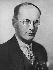 monohrome photograph of a man, wearing glasses