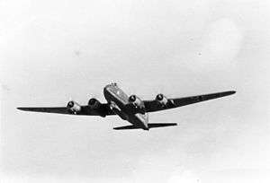 A black and white photo of the belly of a four engined monoplane in flight