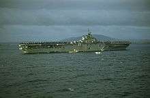 A color photo of an aircraft carrier at sea from a distance