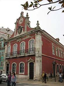Former town municipal hall on Praça da República. Two stories. Dark pink. Clock atop building.