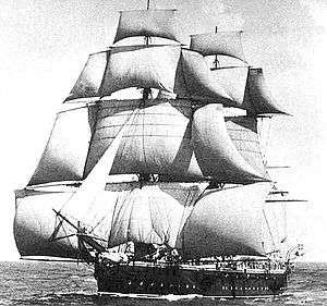A sailing ship running with the wind, coming toward the observer at an oblique angle, with squaresails and studding sails set on her masts and a headail set from the bowsprit