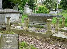 A grave in the shape of a granite sarcophagus fenced by chained bollards