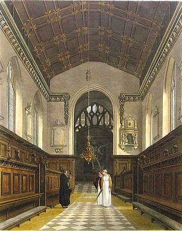 A chapel with a narrow chancel arch with memorials either side, black and white tiles on the floor, decorated wooden benches on each side of the aisle, and a painting in front of the main window. A man in dark academic or clerical robes talks to two women wearing bonnets and white dresses.