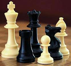 A selection of black and white chess pieces on a chequered surface.