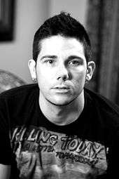 Black and white picture of a man wearing a printed T-shirt and earrings in both earlobes