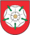 A coat of arms depicting a white flower in the middle that has a yellow stamen and green leaves all on a red background