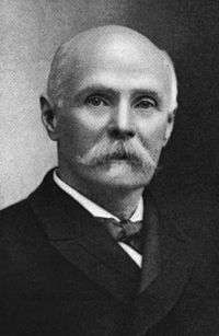 A black and white photographic portrait of a mustached Robert White in his laster years.