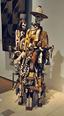 A photo of a complex wooden carving of animals, people and spirits laid on each other to about 2 meters in height