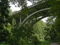 An art deco styled concrete bridge over a wooded ravine