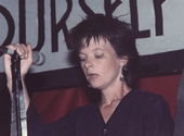 Woman in punk haircut holding microphone on stand