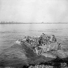 A black and white image of soldiers crossing a body of water in an amphibious vehicle