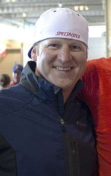 A chest and head shot of a white male, wearing a white baseball cap backwards and navy blue fleece top.